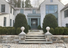 Entrance of the residence with stone steeps leading up the the stone house with a green door