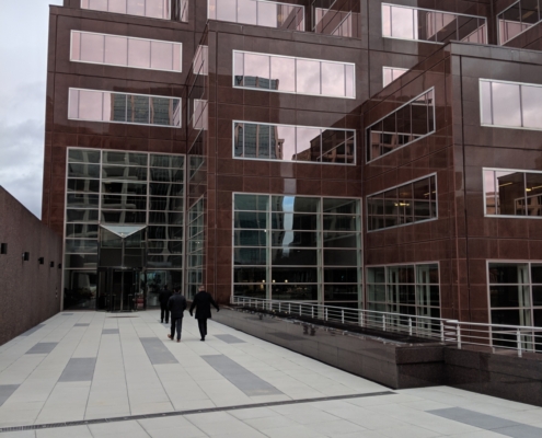 Pedestrian bridge pictured from onto of it looking toward a tall building