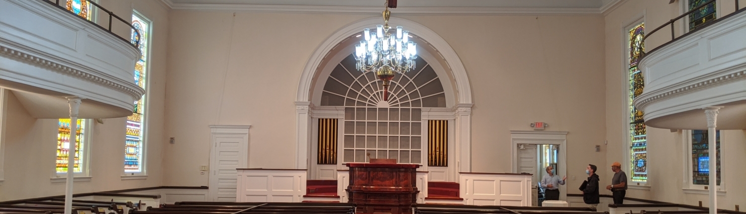 Inside of a church with rows of pews and large chandelier