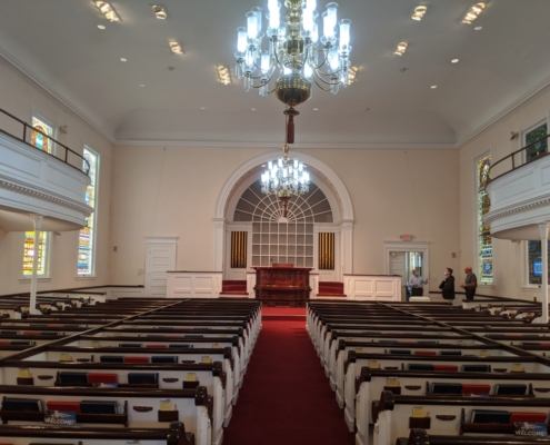 Inside of a church with rows of pews and large chandelier